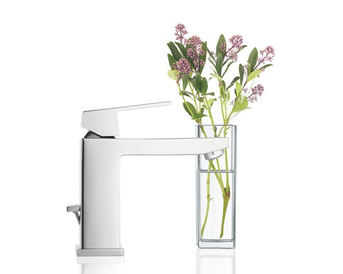 Lesklá armatúra vedľa vázy s kvetinami.