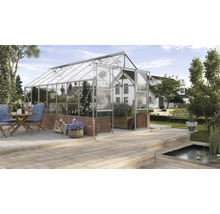 Skleník so sklenenými stenami a murovaným základom v záhrade