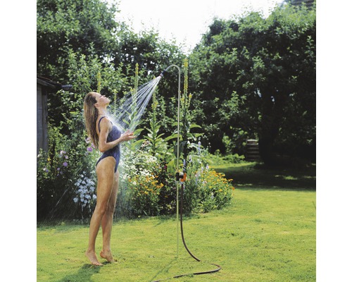 Žena pod záhradnou sprchou v záhrade.