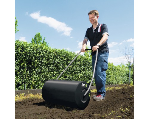 Muž používa záhradný valec for.q v záhrade.