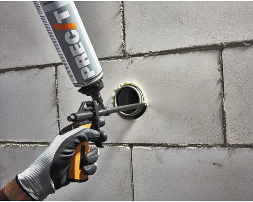 Na stenu sa nanáša dóza stavebnej peny pištoľou na utesnenie rúrky.