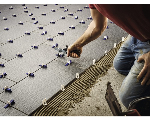 Dlaždič pokladá dlaždice pomocou nivelačného systému