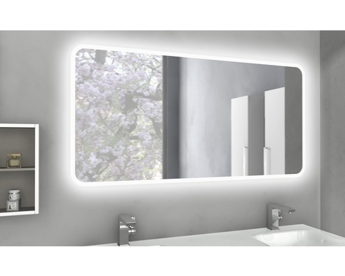 Osvetlené kúpeľňové zrkadlo nad umývadlom s armatúrami a malou poličkou.