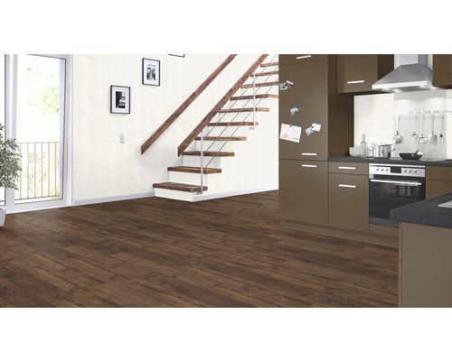 Interiér s hnedou laminátovou podlahou, schodiskom, kuchyňou a balkónom.