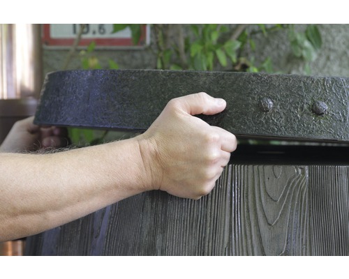 Osoba otvára drevenú nádrž na dažďovú vodu