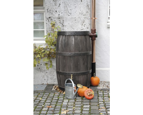 Drevený dažďový sud s kohútikom, kovová krhla a tekvice v záhrade.