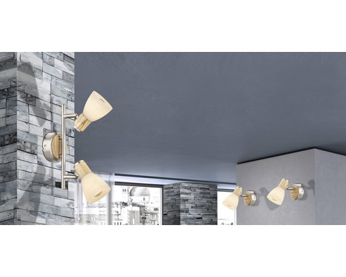 Obývacia izba s niekoľkými nástennými svietidlami so sklenenými tienidlami a drevenými detailmi.