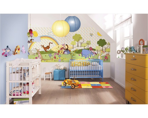 Detská izba s tapetou Macko Pu, modrou detskou postieľkou, prebaľovacím pultom a žltou komodou.