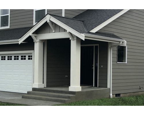 Pohľad na dom s garážou a strieškou pri vchode.