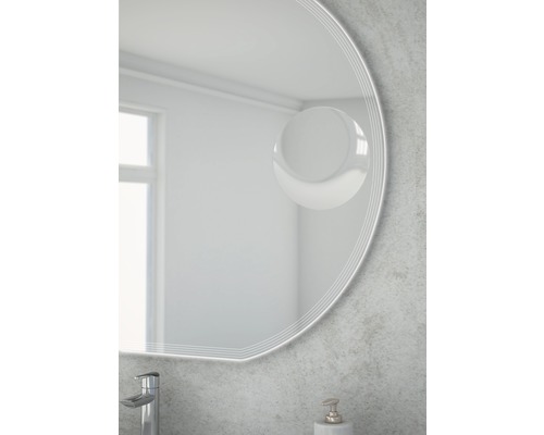 Detail okrúhleho zrkadla v kúpeľni s vodovodnou batériou a dávkovačom mydla