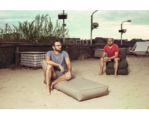 Dvaja muži relaxujú na piesočnej ploche s exteriérovým nábytkom.