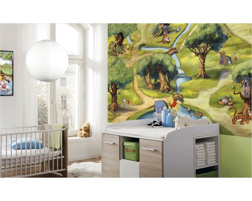 Detská izba s tapetou Macka Pú, detskou postieľkou a prebaľovacím pultom pre detskú výbavu.