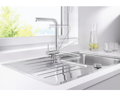 Nerezová drezová batéria s otočným výtokom vo svetlej kuchyni.