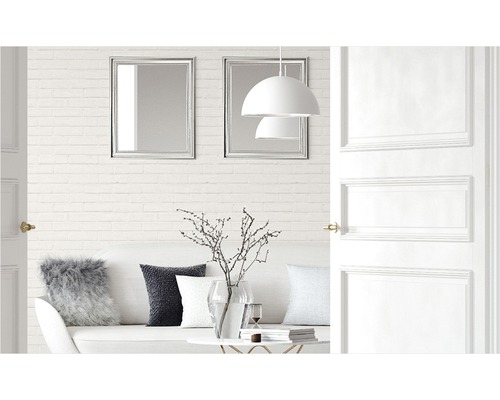 Svetlá obývacia izba s pohovkou, vankúšmi, stolom, dekoráciou, lampami, zrkadlami a otvorenými dverami.