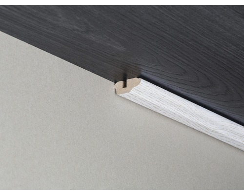 Podlahová lišta medzi stenou a tmavou laminátovou podlahou