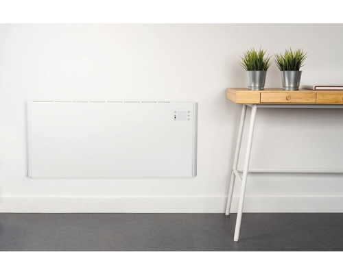 Nástenný konvektorový ohrievač v miestnosti so stolom a dekoráciou