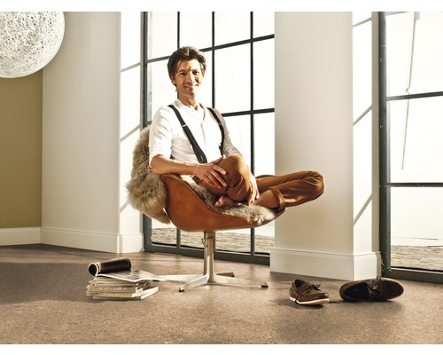 Svetlá miestnosť s korkovou podlahou a muž v hnedom kresle