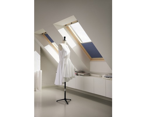 Svetlá podkrovná izba s dvoma strešnými oknami, roletami a krajčírskou figurínou so šatami