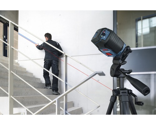 Stavenisko s čiarovým laserom na statíve a remeselníkom na schodoch
