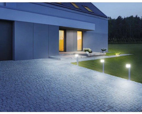 Osvetlený vonkajší priestor domu s trávnikom a kamennou cestou