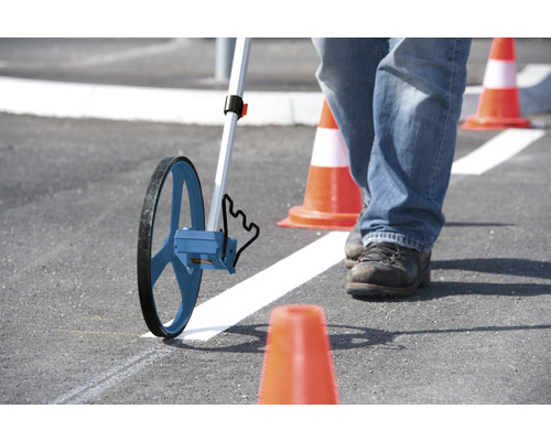 Osoba meria meracím kolieskom na asfalte