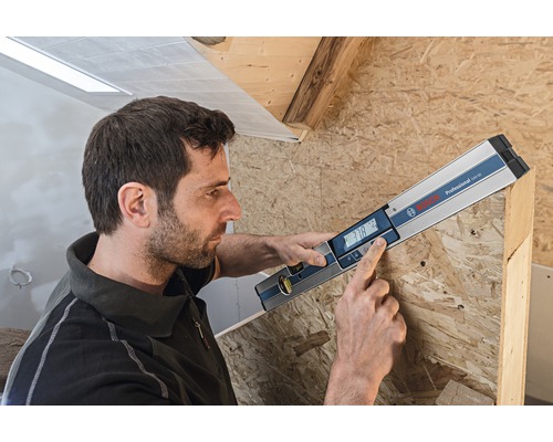 Muž používa digitálnu vodováhu Bosch na meranie dreva