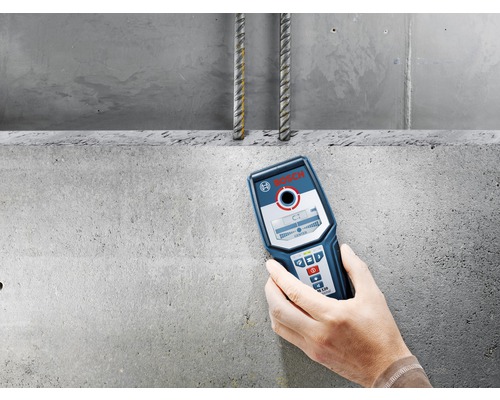 Ruka drží detektor loga Bosch pred betónovou stenou s výstužou