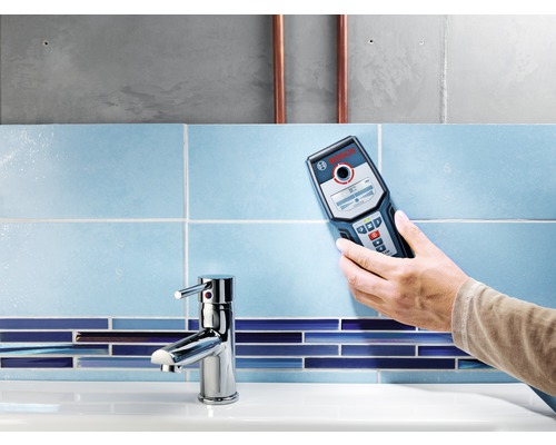 Ruka drží detektor Bosch na obloženej stene kúpeľne