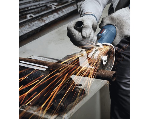 Osoba reže kovovú rúrku uhlovou brúskou, z ktorej odletujú iskry.