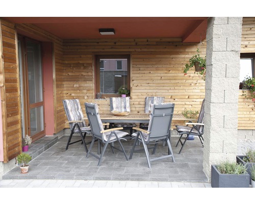 Vonkajšie sedenie so stolom a stoličkami na terase pred dreveným domom