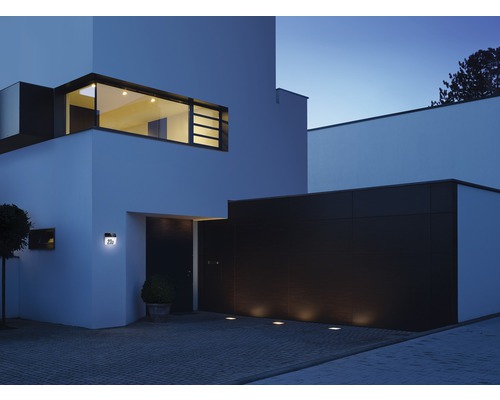 Moderný dom s vonkajším osvetlením na fasáde a príjazdovej ceste