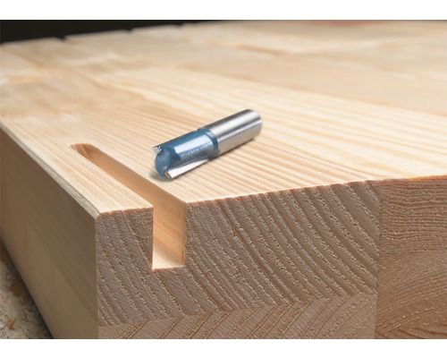 Drážkovacia fréza vedľa drevenej dosky s vyfrézovanou drážkou