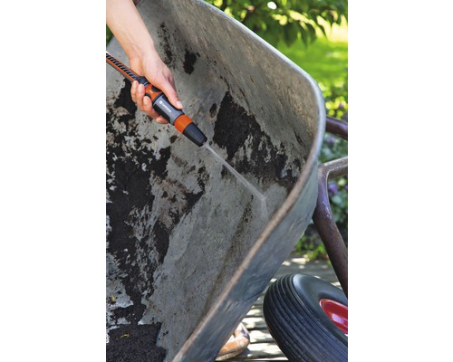 Osoba čistí špinavé koliesko záhradným postrekovačom.