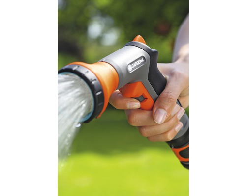 Ruka drží záhradnú sprchu Gardena, z ktorej prúdi voda.