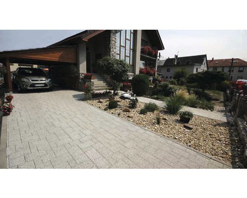 Príjazdová cesta s dlažobnými kockami, prístrešok pre auto a dom s kamennou fasádou