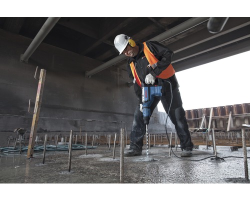 Stavebný robotník vŕta do betónu vŕtacím kladivom