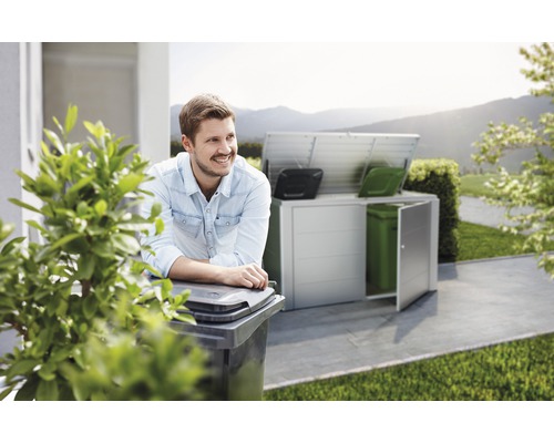 Scéna s mužom opierajúcim sa o smetný kôš a úložným priestorom na smetné koše v pozadí.