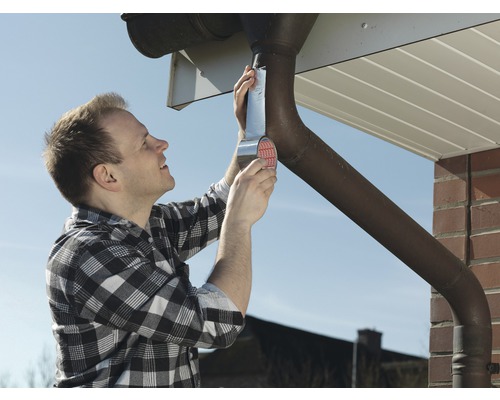 Muž opravuje odkvap pomocou tesniacej pásky.