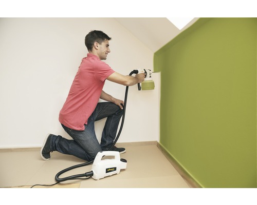 Muž natiera stenu pomocou striekacieho systému na farby