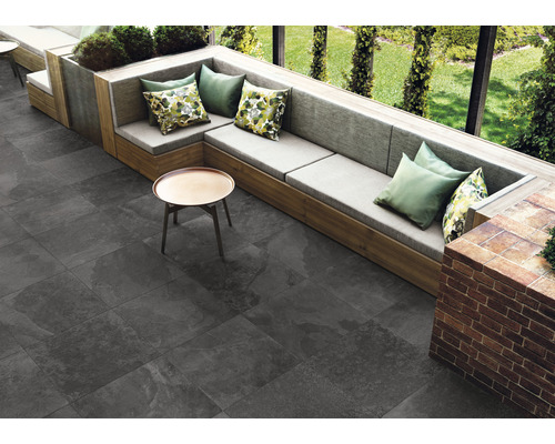 Vonkajší priestor so sivou dlažbou, sedenie s vankúšmi a malým stolom