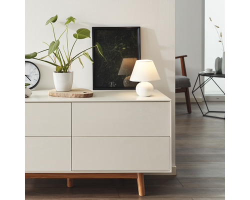 Komoda v obývacej izbe so stolnou lampou, izbovou rastlinou a obrazom