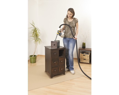 Žena lakuje nočný stolík pomocou systému na striekanie farby