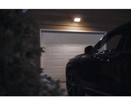 Scéna s garážou osvetlenou stropným svietidlom a autom pred ňou.