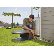 Muž inštaluje robotickú kosačku na trávu v záhrade