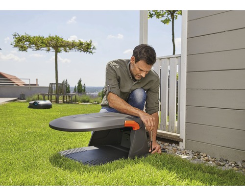 Muž inštaluje robotickú kosačku na trávu v záhrade