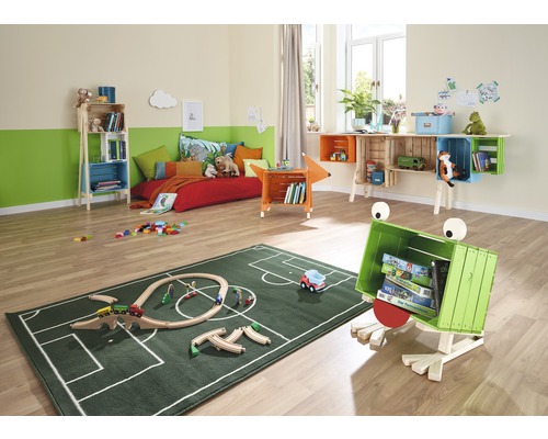 Detská izba s posteľou, regálmi z drevených debničiek a zeleným kobercom so vzorom futbalového ihriska.