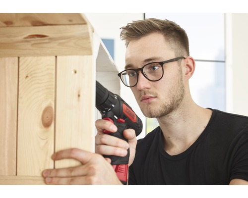 Muž pracuje s akumulátorovým skrutkovačom na drevenej polici