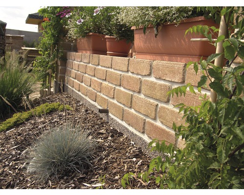 Murovaná stena z tehál s kvetináčmi a záhradnou výsadbou