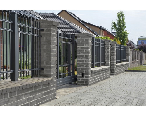 Plot s bránou z kovu a kamenné stĺpy pred obytným domom