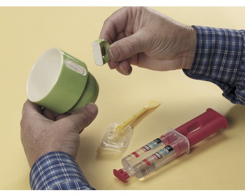 Osoba lepí zlomené ucho na šálku pomocou kombinovaného lepidla.